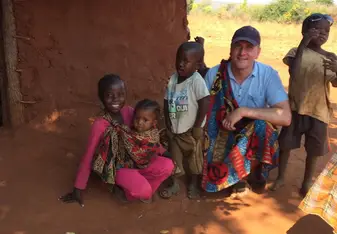 Man in Zambia with four kids crouching down outside
