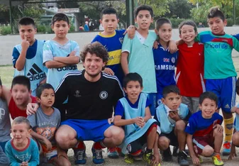 international volunteer together with many children from the sports program smiling to the camera