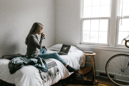 Student sitting on bed drinking tea