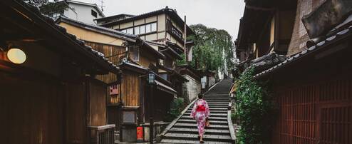 A woman in a kimono walks up a staircase outside.
