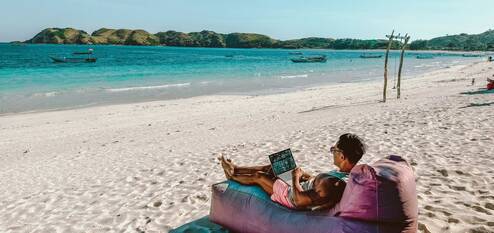 Man working on a laptop on the beach.