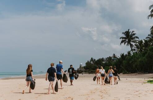 Volunteers carry trash bags down a beach.