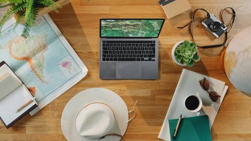 Flatlay of laptop, map, and hat