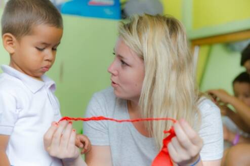 Volunteer assisting a young boy with his ribbon in Ecuador