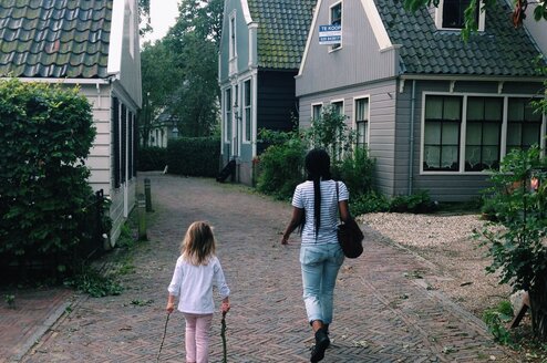 little girl and woman walking on cobblestone street