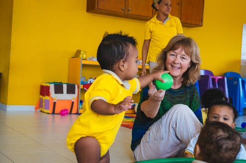 Toddler and senior volunteer playing with a ball