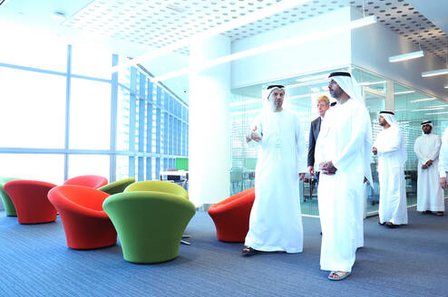 Khalifa University directors and leadership walk through the modern campus in traditional Arabic clothes. 