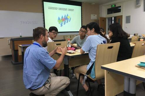students around a table learning with powerpoint in the background