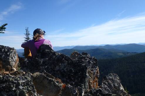 girl on mountaintop overlooking view of mountains in Montana
