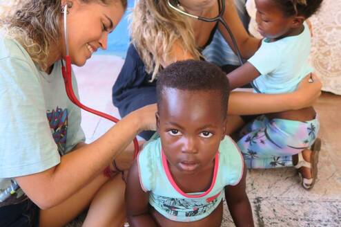 Two Volunteers doing a health screen of the children at the kindergarten
