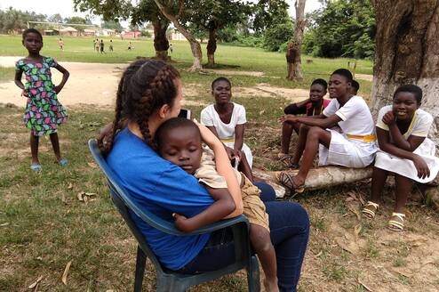 A young Kenyan child child sleeps in the arms of a female Village Book Builders volunteer.