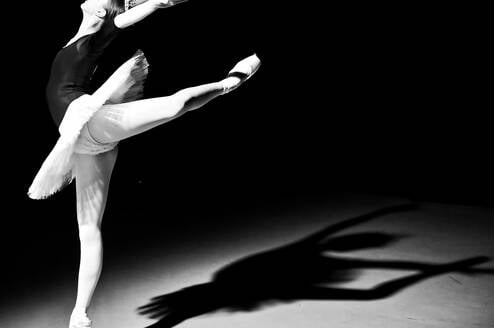 Black and white photo of a ballerina with her leg in attitude position.