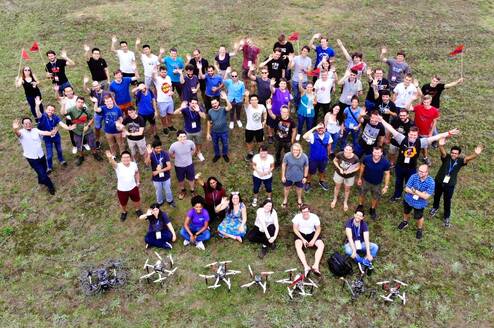 Students stand in a field with the drones they have just built and flown.