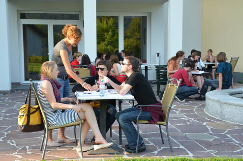 Participants sitting around tables on the terrace and talking