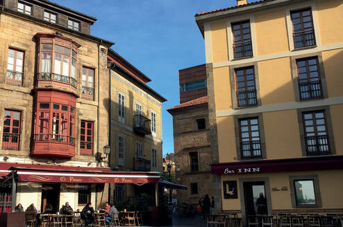 Two orange-toned, sunlit buildings with cafes at the bottom