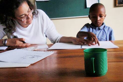 Volunteer in Tanzania helping a student with a reading assessment 