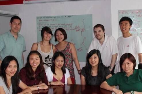A group of ten interns sitting around a table and smiling at the camera.