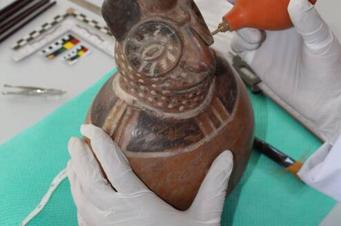 Cleaning a Moche ceramic vessel
