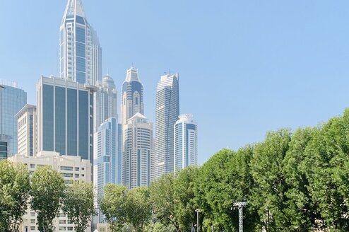 Students on the green AUD campus with the Dubai skyline in the background.