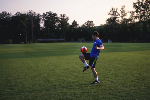 Man balancing a soccer ball on his leg.