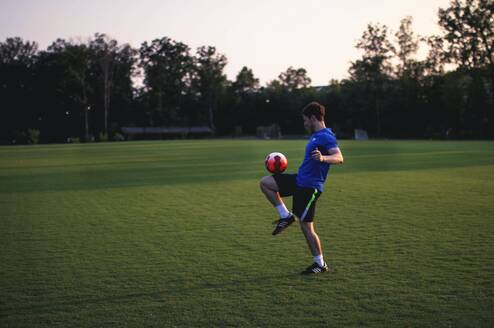 Man balancing a soccer ball on his leg.