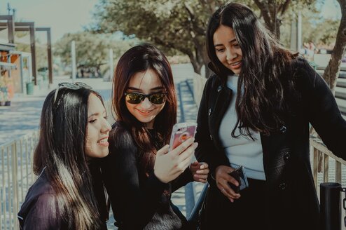 Three women looking at a cell phone.
