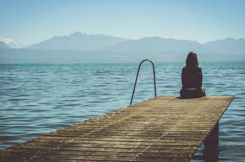 Woman sitting on a dock near the water.