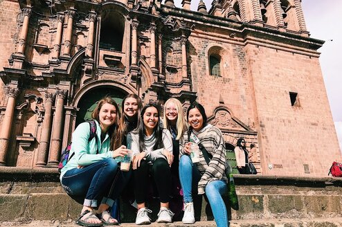 Five women sitting in front of a historic building in Ecuador.
