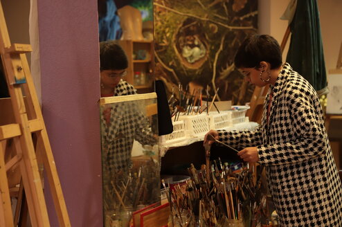 Student looking at paint brushes in class