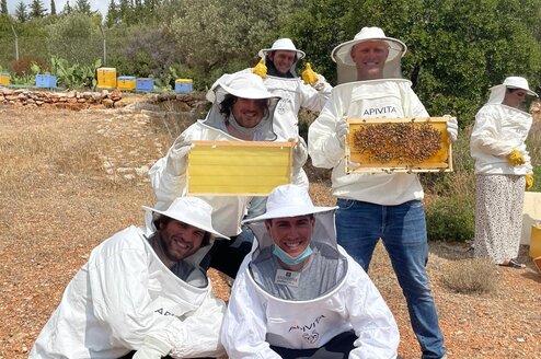 students in protective clothing showing off beekeeping