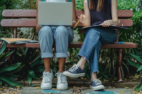 Two students sitting on a bench using a laptop