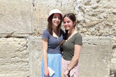 Two women stand in front of the Western Wall