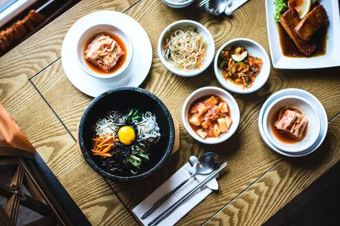 Several bowls on a table with various Korean foods in them.