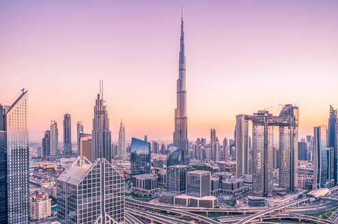 A city landscape of Dubai with an orange and purple sunset