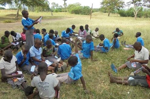 A girl child leading the rest of the children to read and concentrate on what took them to school.
