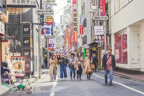 Five women stand on a shopping street in Japan.