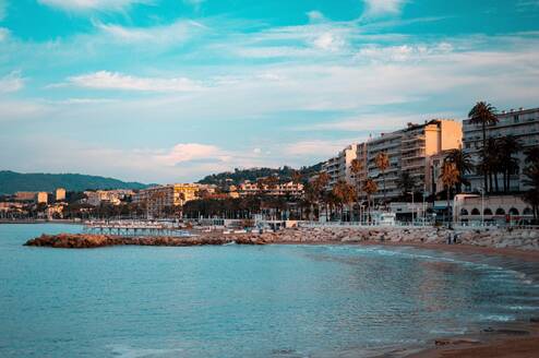 A sunny beach with houses rising along it