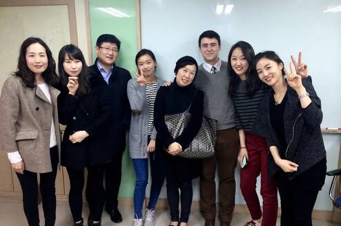 A teacher poses with a group of smiling students.