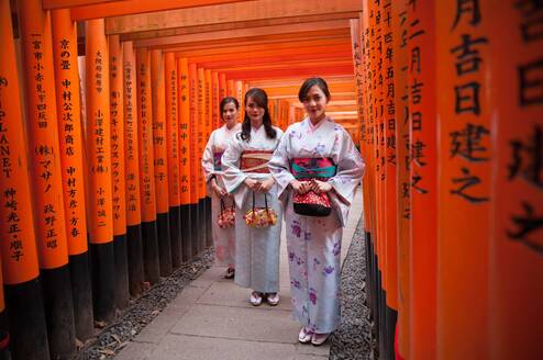 Three women stand in traditional Japanese dress.