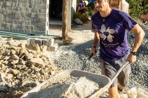 Volunteer moves wheelbarrow full of dirt