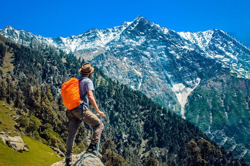 A man stands facing a valley and mountains.