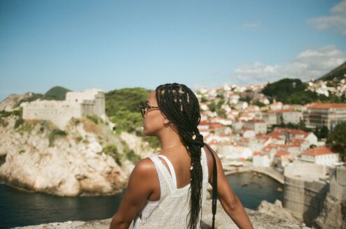 Woman looks to the side with buildings along a bay in front.