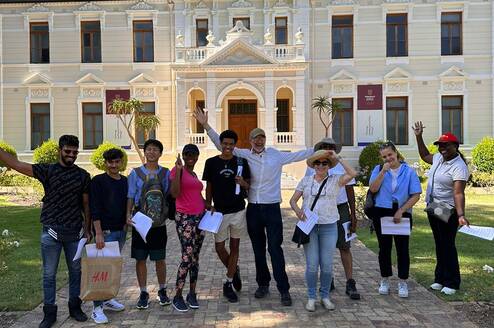 Group of diverse male and female students standing in front of university building