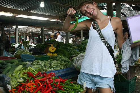 a teacher poses with a chili in a thailand market