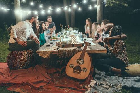 People socialize around a table outside at night.