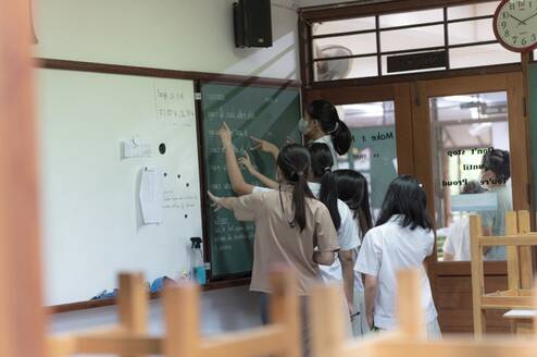 Teacher showing students work on chalk board