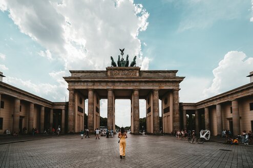 A woman stands in front of large stone gate in Germany.