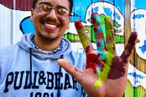 A student holding up a hand with paint on it 