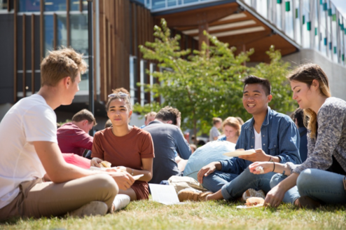 Group of students sitting together on grass 