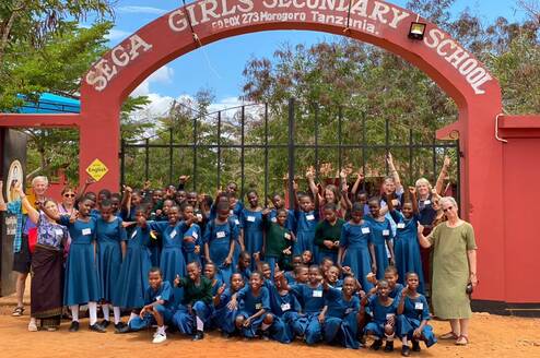 2023 volunteer group and students under SEGA School sign 